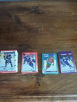 Four stacks of 1990 and 1991 Score hockey cards on a wooden table, showing front card faces and edges of cards to indicate quantity and condition.