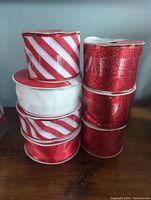 Stacked view of wired ribbons showing red/white diagonal stripes, solid white, solid red satin, and red glitter designs.