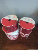 Top view of seven rolls of wired Christmas ribbon showing sparkle glitter and striped designs, brand Celebrate It on the spool tops.