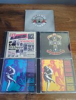 Top view showing all five CDs in cases with covers and slip case on wooden surface.