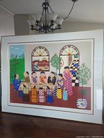 Full view of framed print leaning against wall beneath chandelier