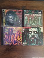 Front view of four CD albums in jewel cases: Rob Zombie Hellbilly Deluxe, White Zombie Astro-Creep 2000, White Zombie album, Rob Zombie Past Present & Future. Each case has unique album cover art visible.