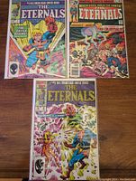 Overview of three Marvel The Eternals comics, issues #1, #2, #9 on wooden surface showing front covers.