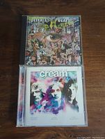 Photo of two Cream CD albums: 'Disraeli Gears' with psychedelic collage cover art and 'The Very Best of Cream' with a purple-blue band portrait cover.
