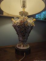 Front view showing porcelain body with cherubs, flowers and lamp shade