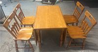 Full view of the maple dining table with four chairs around it, showing the style and finish of the set