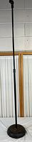 Full view of a tall black weighted microphone stand with adjustable height.