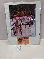 Full view of framed photo showing both goaltenders wearing Team Canada jerseys and goalie pads, holding flowers and gold medals.