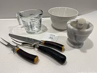 Overview of all items including marble pestle and mortar, mixing bowl, glass measuring cup, and carving tools on white surface.