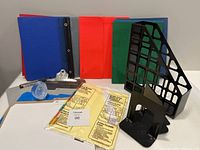 Overall shot showing the paperweight, colorful folders, clipboards, black plastic bookends, and ring binder index pages.