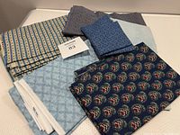 Photo showing multiple folded quilting fabric pieces in various blue shades and patterns, including floral and geometric prints.