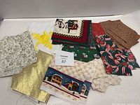 Photo showing all quilting material pieces including various Christmas and winter themed fabrics in different colors and patterns.
