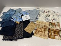 Overview of multiple quilting fabric pieces featuring blue and nature themes spread out on a white background.