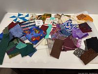 Yarn colour organizer visible with multiple fabric pieces in varied colours and patterns spread alongside it.