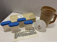 Photo showing four off-white plastic spice containers each with blue two-piece lids, storage box, and sheet of spice names