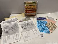 Cross-stitch project materials including pattern sheets, embroidery threads, fabric, and hoop.