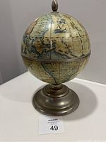 Photo showing front and partial side view of vintage globe ice bucket with metal base on white surface.