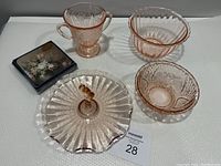 Front overview of vintage pink glass sugar bowl, two small bowls, wavy tray, and coasters set