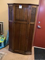 Front view of dark stained oak wardrobe with carved panels and ring pull hardware