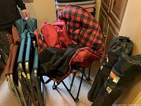 Set of camping chairs and carrying bags including oversized red plaid chair, teal chair, and two folded chairs with bags