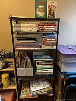 Full view of the books on the black metal shelving including boxed sets on top shelf and various books on other shelves