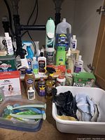 Wide view of assorted cleaning supplies under a sink including detergents, sprays, and cleaning tools