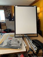 Front view of table-top easel stand with easel pads and carrying cases stacked on table