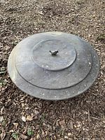 Top view of the metal fire pit lid showing a bird-shaped handle.