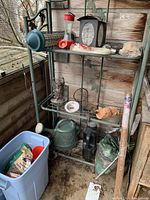 Full view of metal folding baker's rack with various garden tools and accessories on wooden deck near wall