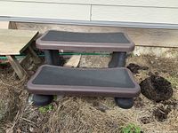 Plastic curved 2-step unit with non-skid tread surface on each step placed outdoors on ground.