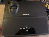 Top view of InFocus IN112 projector showing control buttons and lens area.