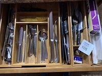 Set of stainless steel cutlery and kitchen knives arranged in bamboo trays
