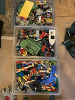 Top view of 3 large bins filled with assorted LEGO pieces including bricks, plates, base pieces, minifigure parts, and vehicle elements.