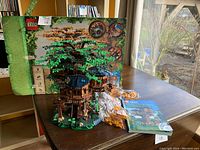 Assembled treehouse model displayed with retail box, manual and extra leaf bags on table