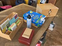 Overall shot showing three-piece wooden desk organizer set, red leather box, blue printer paper reams, and two wooden storage boxes.