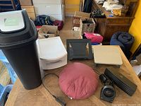 Overall view of office supplies including garbage bin, drawer, fan, laptop stand, speaker, footrests, and USB hub on table and floor