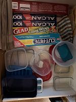 Top view showing assortment of plastic containers with lids and blue silicon ice cube tray, partial view of kitchen wraps and paper bags.