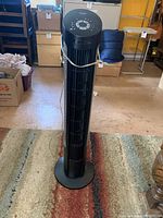 Front full view of tall black Seville Classics tower fan showing vertical vents and round base.