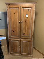 Front view of the entire wood cabinet with four doors closed showing natural wood grain and finish.