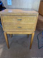 Front view of wooden side table showing two drawers and tapered legs
