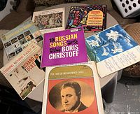 Photo showing a collection of 8 vintage vinyl records with various titles and artists, laid out on a table.