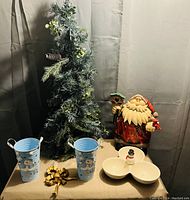 Artificial Christmas tree, Santa figurine, decorative snowman buckets, and snowman dish on table