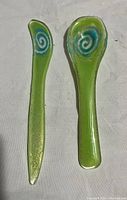 Photo of green glass knife and spoon utensils with swirl design on handles.