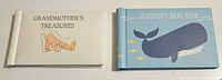 Photo showing two keepsake photo albums with grandmother themes: one cream-colored with a baby image and title 'GRANDMOTHER'S TREASURES', the other light blue with a whale fish illustration and title 'GRANDMA'S BRAG BOOK'.