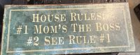 Front view of the rectangular metal wall plaque showing house rules text in gold on dark green background.