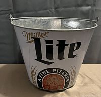 Front and side view of a metal bucket with Miller Lite branding on it and a metal handle attached to the rim.