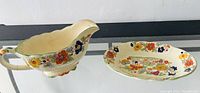 Gravy boat and tray showing floral patterns, scalloped edges and handle detail.