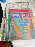 Top view photo showing a stack of multiple colorful abstract expressionist artworks, mixed media, unframed, by Paco Engels