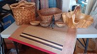 Multiple woven baskets, artisan wooden bowls, and woven mat displayed on a table.