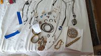 Overview of assorted costume jewelry items laid out on white surface including necklaces, earrings, bracelets, and decorative pieces.